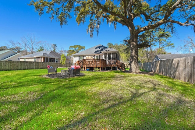 view of yard with a wooden deck, a fenced backyard, and a sunroom