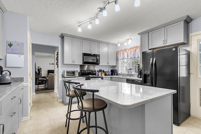 kitchen featuring sink, a textured ceiling, a kitchen island, and black appliances