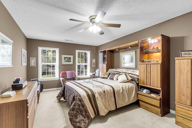 carpeted bedroom featuring ceiling fan and a textured ceiling