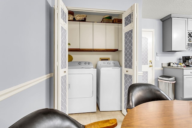 clothes washing area featuring cabinets, separate washer and dryer, a textured ceiling, and light tile patterned floors