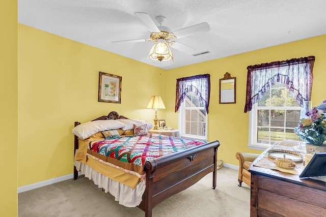 bedroom with ceiling fan, light colored carpet, and a textured ceiling