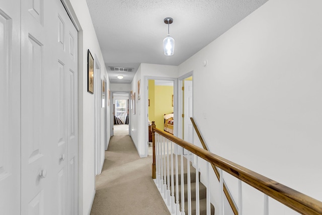 hall featuring light colored carpet and a textured ceiling