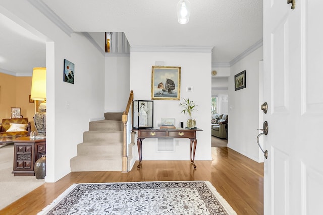 entryway with a textured ceiling, light hardwood / wood-style flooring, and ornamental molding