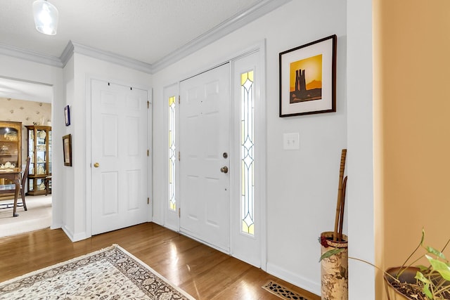 entryway featuring hardwood / wood-style floors, ornamental molding, and a textured ceiling