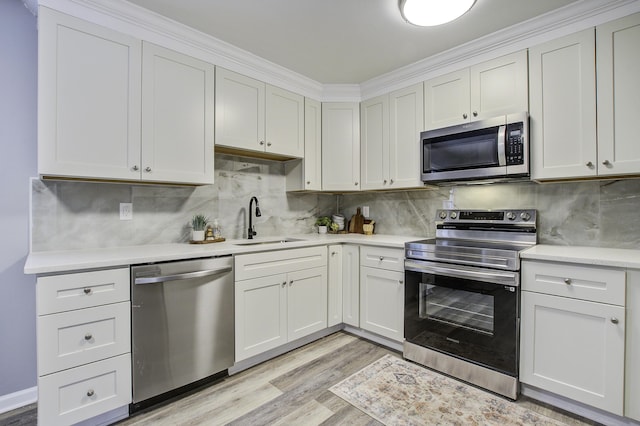 kitchen with white cabinetry, stainless steel appliances, sink, and tasteful backsplash