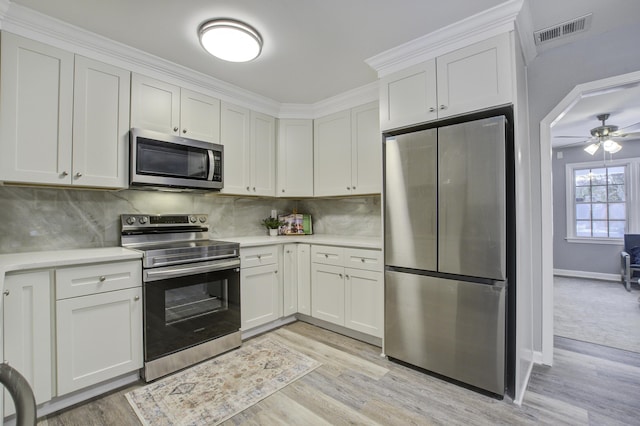 kitchen featuring white cabinetry, appliances with stainless steel finishes, decorative backsplash, and light wood-type flooring