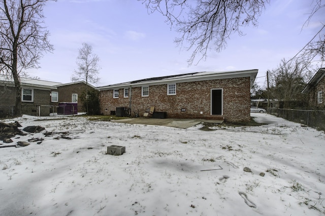 snow covered house featuring central AC unit