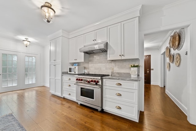 kitchen with light stone countertops, hardwood / wood-style floors, white cabinetry, premium stove, and backsplash