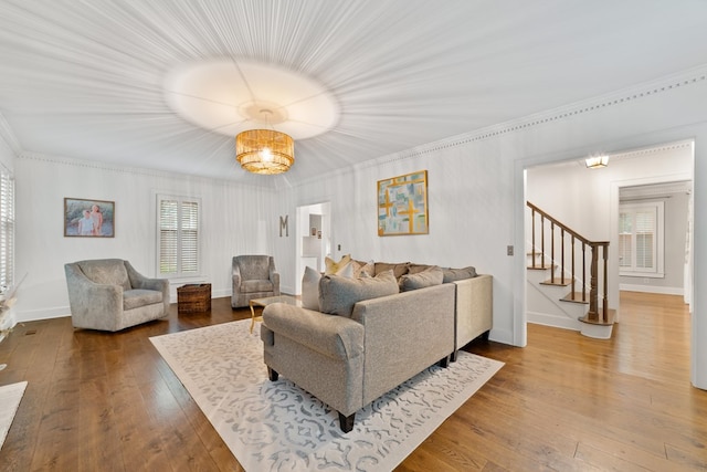 living room with wood-type flooring, crown molding, and an inviting chandelier