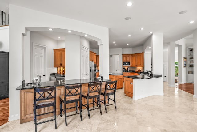 12 Port Tack, Hilton Head Island, SC 29928 - kitchen featuring a peninsula, arched walkways, brown cabinetry, recessed lighting, and a kitchen breakfast bar