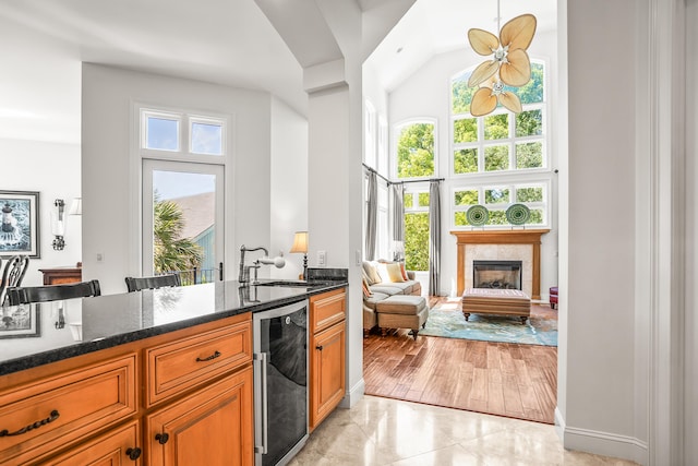 12 Port Tack, Hilton Head Island, SC 29928 - kitchen featuring a sink, high vaulted ceiling, dark stone countertops, brown cabinets, and a glass covered fireplace