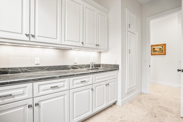 12 Port Tack, Hilton Head Island, SC 29928 - kitchen featuring white cabinetry, a sink, baseboards, and dark stone counters