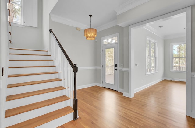 entrance foyer with ornamental molding, light wood-style flooring, baseboards, and stairs