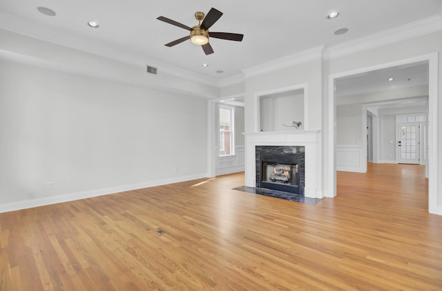 unfurnished living room featuring light wood-type flooring, crown molding, and a high end fireplace