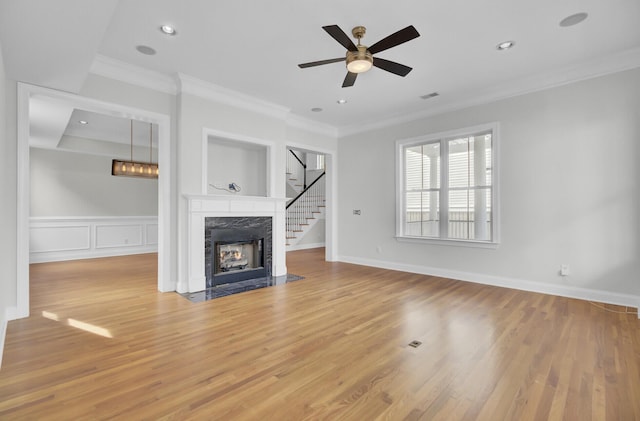 unfurnished living room with light wood-style floors, crown molding, and a high end fireplace