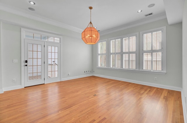 unfurnished room with light wood-style floors, a healthy amount of sunlight, visible vents, and crown molding