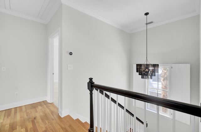 hallway with visible vents, ornamental molding, an upstairs landing, wood finished floors, and baseboards