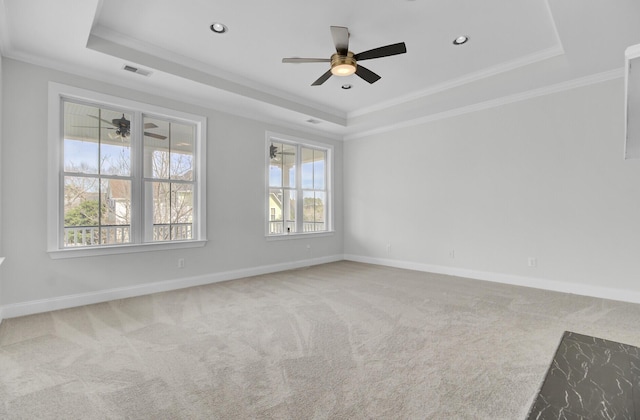 spare room featuring a tray ceiling, visible vents, and carpet flooring