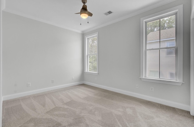 spare room with a wealth of natural light, visible vents, crown molding, and light carpet