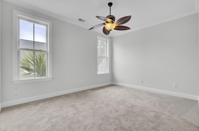 carpeted empty room with visible vents, ornamental molding, ceiling fan, and baseboards