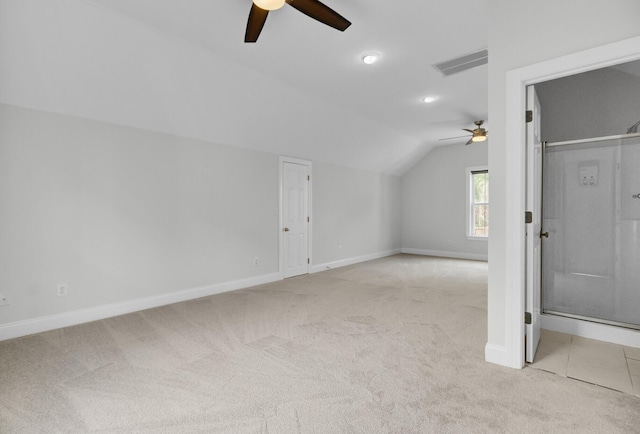 additional living space featuring light colored carpet, a ceiling fan, baseboards, vaulted ceiling, and visible vents