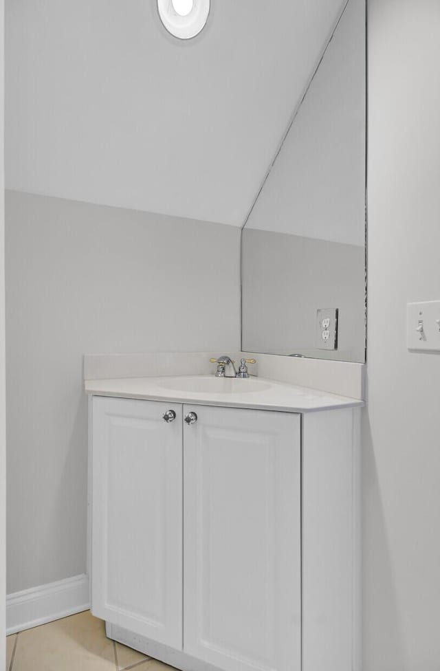 bathroom featuring vaulted ceiling, vanity, and baseboards