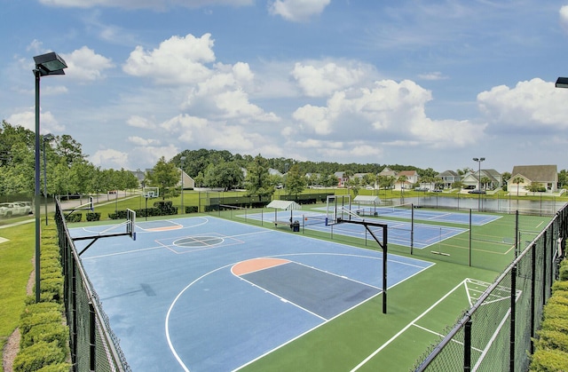 view of basketball court featuring community basketball court, a water view, a tennis court, and fence