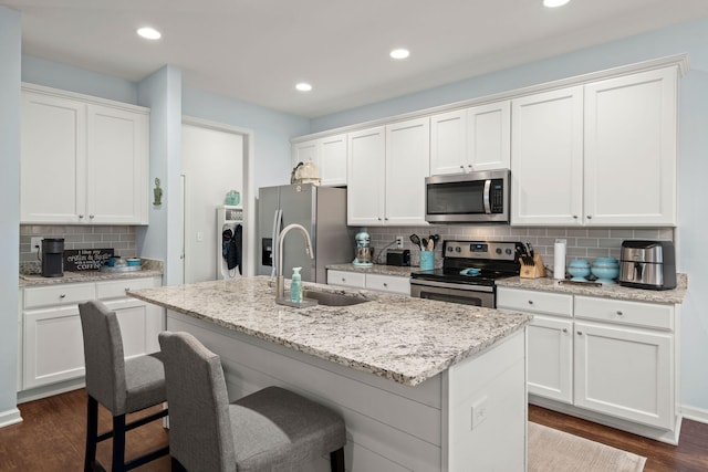 kitchen featuring white cabinets, stainless steel appliances, and a kitchen island with sink