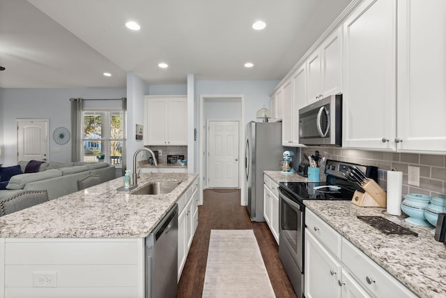 kitchen with sink, an island with sink, appliances with stainless steel finishes, dark hardwood / wood-style flooring, and white cabinetry