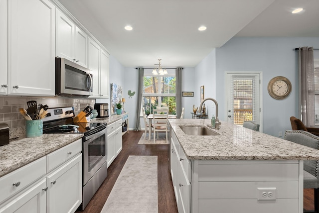 kitchen with sink, dark wood-type flooring, a kitchen island with sink, a breakfast bar, and appliances with stainless steel finishes