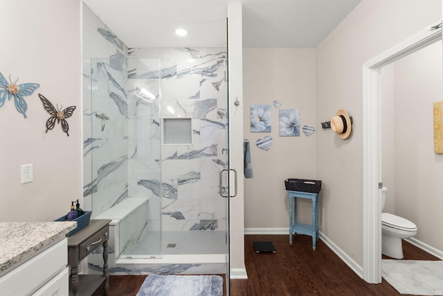 bathroom featuring vanity, hardwood / wood-style flooring, toilet, and a shower with door