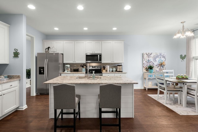 kitchen with sink, stainless steel appliances, white cabinetry, and an island with sink