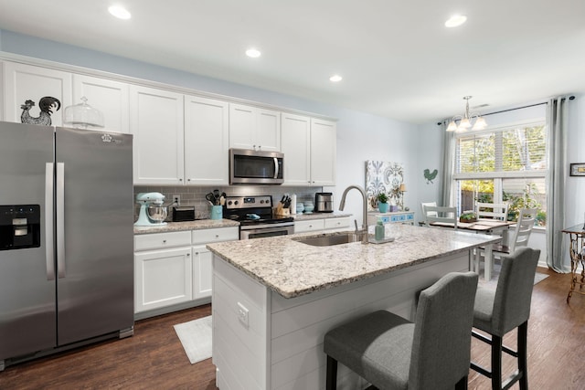 kitchen with dark hardwood / wood-style floors, white cabinetry, a kitchen island with sink, and appliances with stainless steel finishes