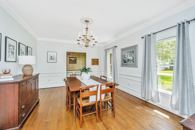 dining area with an inviting chandelier, crown molding, and light hardwood / wood-style flooring