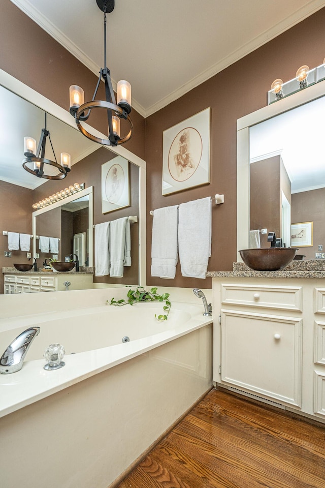 bathroom with a chandelier, a tub to relax in, hardwood / wood-style flooring, ornamental molding, and vanity