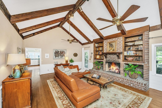 living room with beamed ceiling, a brick fireplace, built in features, and dark hardwood / wood-style flooring