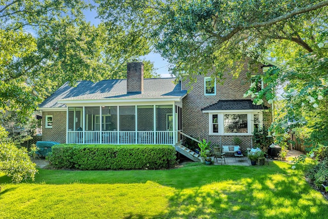 rear view of house with a sunroom, a patio area, and a lawn