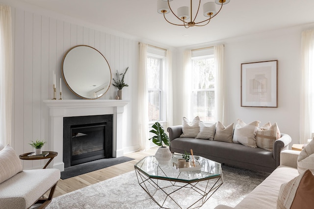 living room with wooden walls, a chandelier, and light hardwood / wood-style floors