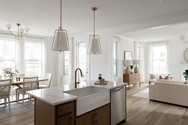 kitchen featuring dishwasher, sink, hanging light fixtures, light hardwood / wood-style flooring, and a center island with sink