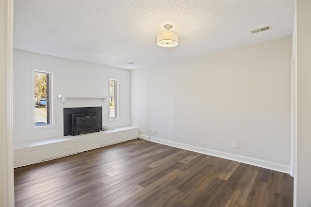 unfurnished living room with dark wood-style floors, a textured ceiling, visible vents, and a healthy amount of sunlight