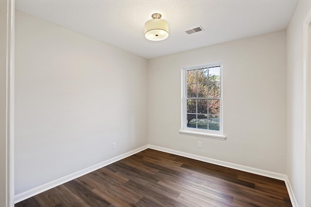 empty room featuring baseboards, a textured ceiling, visible vents, and dark wood-type flooring