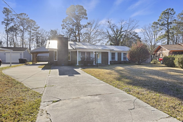 view of front of property featuring concrete driveway, brick siding, a chimney, and a front yard