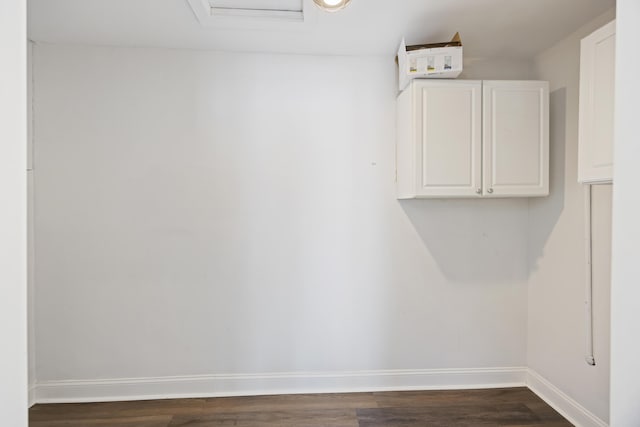 interior space featuring dark wood-type flooring, attic access, and baseboards