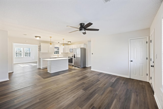 kitchen with stainless steel appliances, light countertops, open floor plan, and white cabinetry