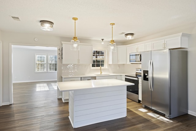 kitchen featuring a center island, stainless steel appliances, light countertops, white cabinetry, and a sink