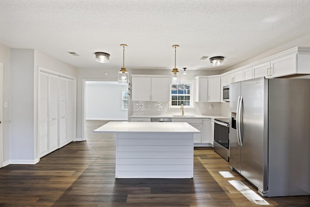 kitchen with stainless steel appliances, a sink, white cabinetry, light countertops, and a center island