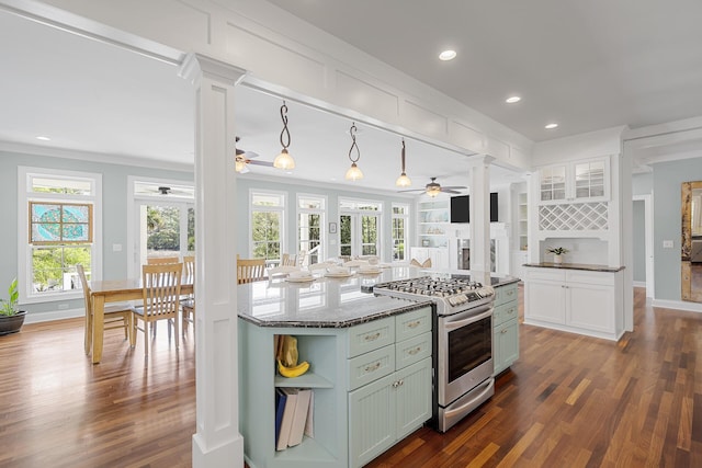 kitchen featuring ornamental molding, ceiling fan, stainless steel range with gas cooktop, dark wood-style floors, and ornate columns