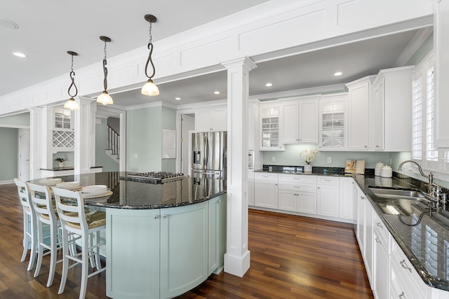 kitchen with a sink, ornamental molding, appliances with stainless steel finishes, decorative columns, and dark wood-type flooring