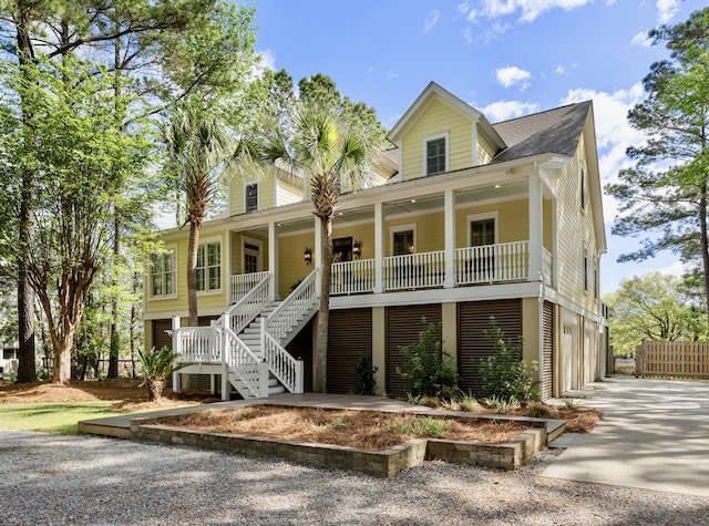 beach home with a garage, stairs, a porch, and driveway