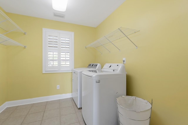 laundry area with laundry area, washing machine and clothes dryer, baseboards, and visible vents
